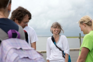 photo of people on a dock near water, woman at center 