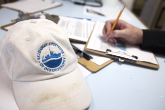 photo of hat and hand writing on clipboard, paper