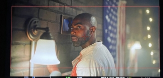 film still of man, with wall light and flag