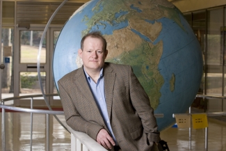 photo of man in front of large globe