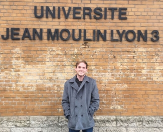 photo of man in front of wall with letters in black