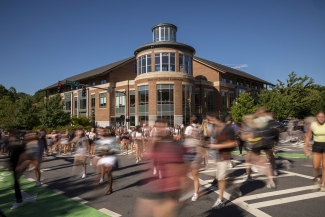 photo of blurred people crossing an intersection, with blue sky