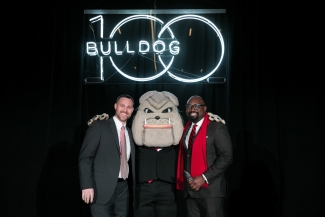 photo of two men with Hairy Dawg mascot and Neon sign