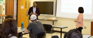 photo of people in a classroom, two standing 