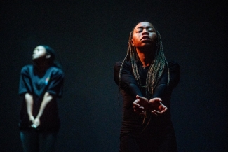 photo of two women on stage with their arms held together at the wrist