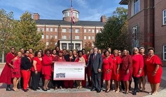 group photo of women wearing red, outdoors, with blue sky and large check