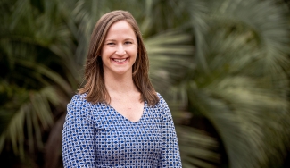 photo of woman with palm fronds in background 