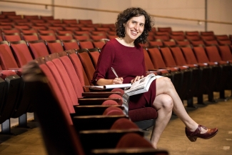 photo of woman seated in auditorium, writing