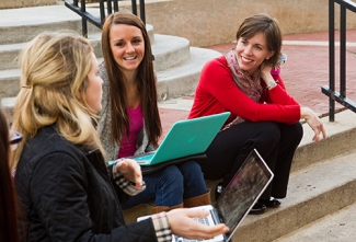 girls on steps, with laptops smiling