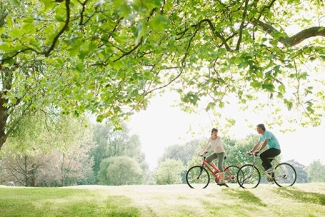 photo of two people biking, day, with field 