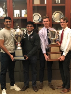 photo of four men holding two trophies 