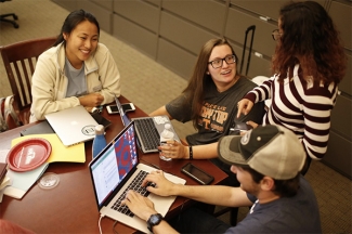 photo of four people at a table, with laptop