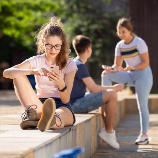 young people outside on their phones