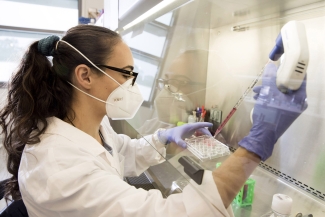 photo of scientists in lab with mask, gloves, pipette