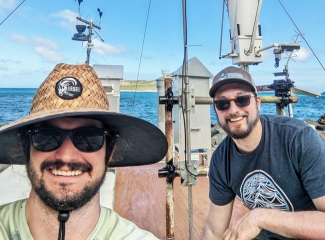 photo of two men, with instruments and sea in background