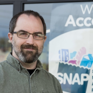 photo of man in front of sign in store window