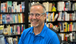 photo of man, bookshelves and books in background