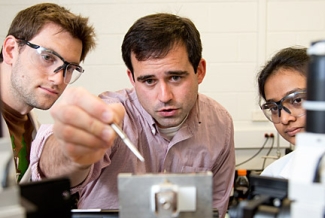 professor in lab, flanked by two students