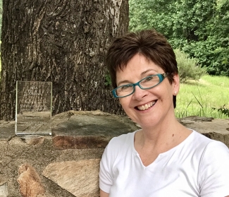 photo of woman outdoors with rock wall and glass plaque