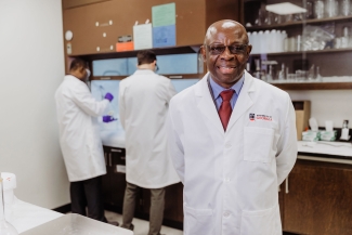 photo of man in lab coat, with two other men in background lab