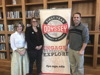 photo of three people with banner and book shelves