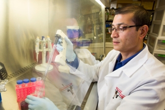 photo of man in lab coat with tubes in isolation chamber