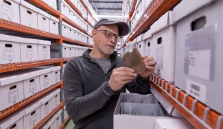 photo of man in aisle of shelves with boxes