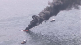 aerial photo of black smoke rising from the ocean water