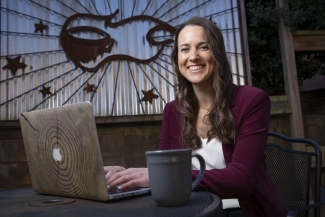 photo of woman with laptop and up of coffee, seated