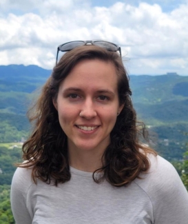 headshot photo of woman, outdoors, mountains in background