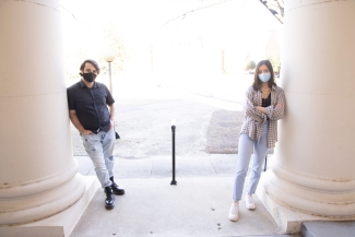 photo of two people leaning against columns, day