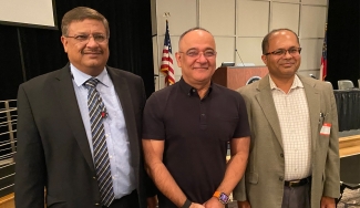 photo of three men, flag and podium in background