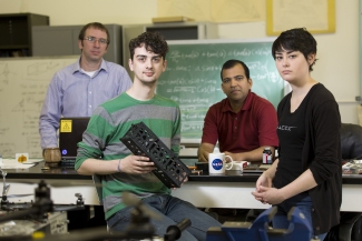 photo of four people in lab, man in foreground with small rectangular box