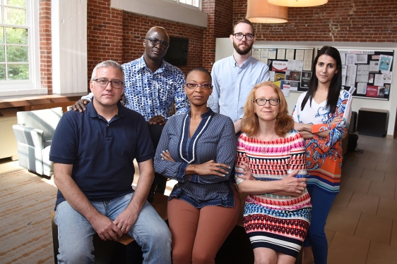 photo of six people, inside with brick wall