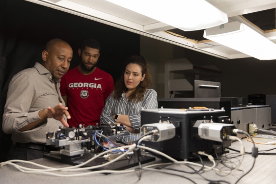 photo of three people with electronic equipment 