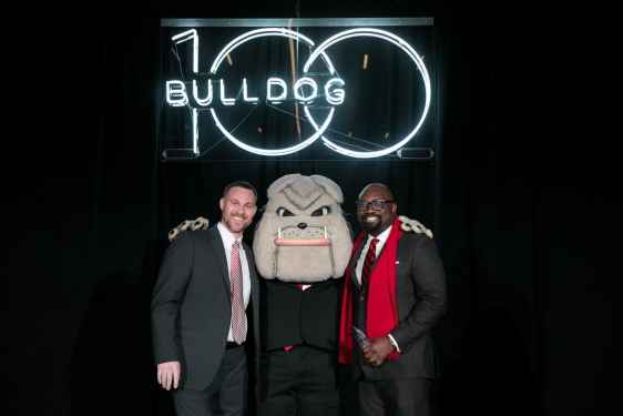 photo of two men with Hairy Dawg mascot and Neon sign