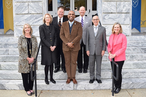 Outdoor photo of seven people on steps of a building