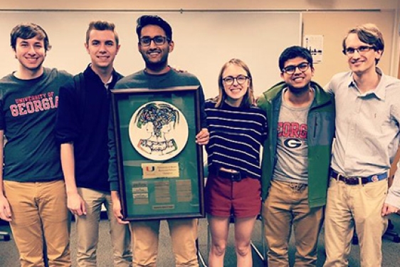 photo of five students with plaque 