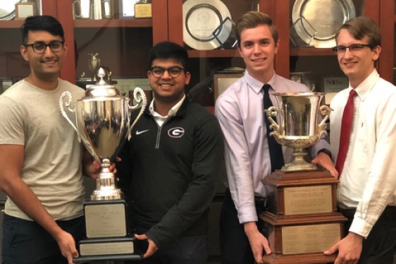 photo of four men holding two trophies 