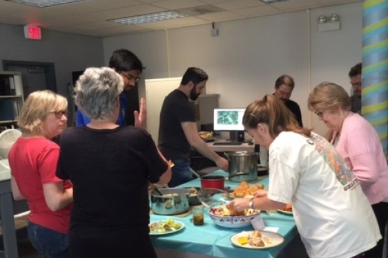 photo of people making plates of food around a table