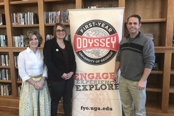 photo of three people with banner and book shelves