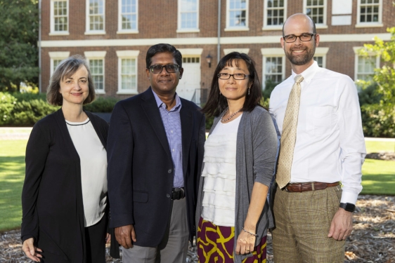 photo of four people, with Old College in background