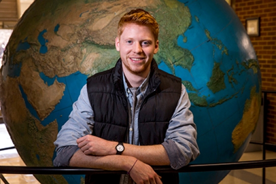 photo of man in front of globe