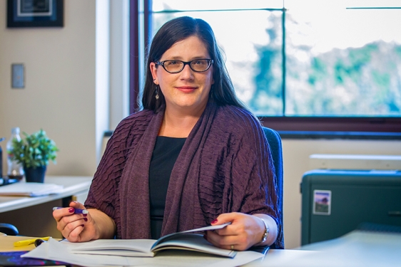 photo of woman in office with book and pen