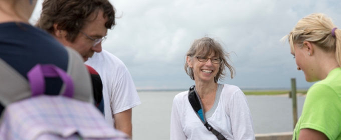 photo of people on a dock near water, woman at center 