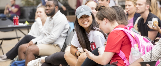 photo of seated outdoor crowd of spectators, two women in foreground