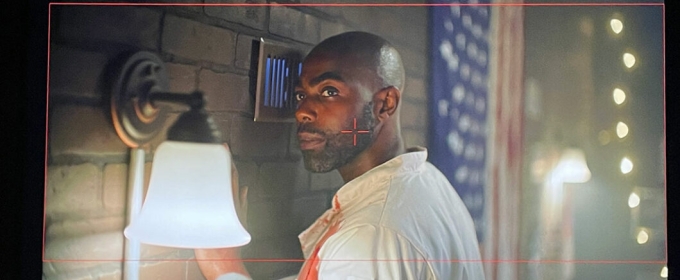 film still of man, with wall light and flag