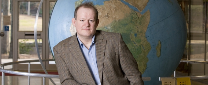 photo of man in front of large globe