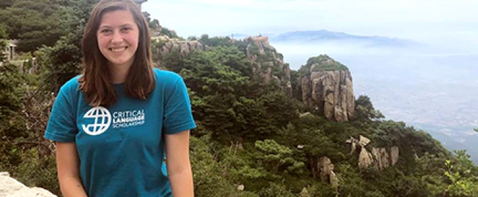 woman sitting on wall, with sky and mountain 