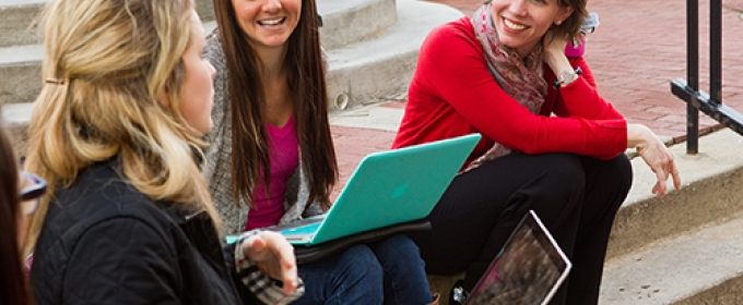 girls on steps, with laptops smiling